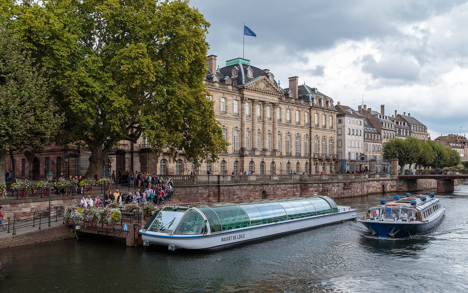 Le barche da escursione navigano sul fiume Ill davanti al maestoso Palais Rohan di Strasburgo.