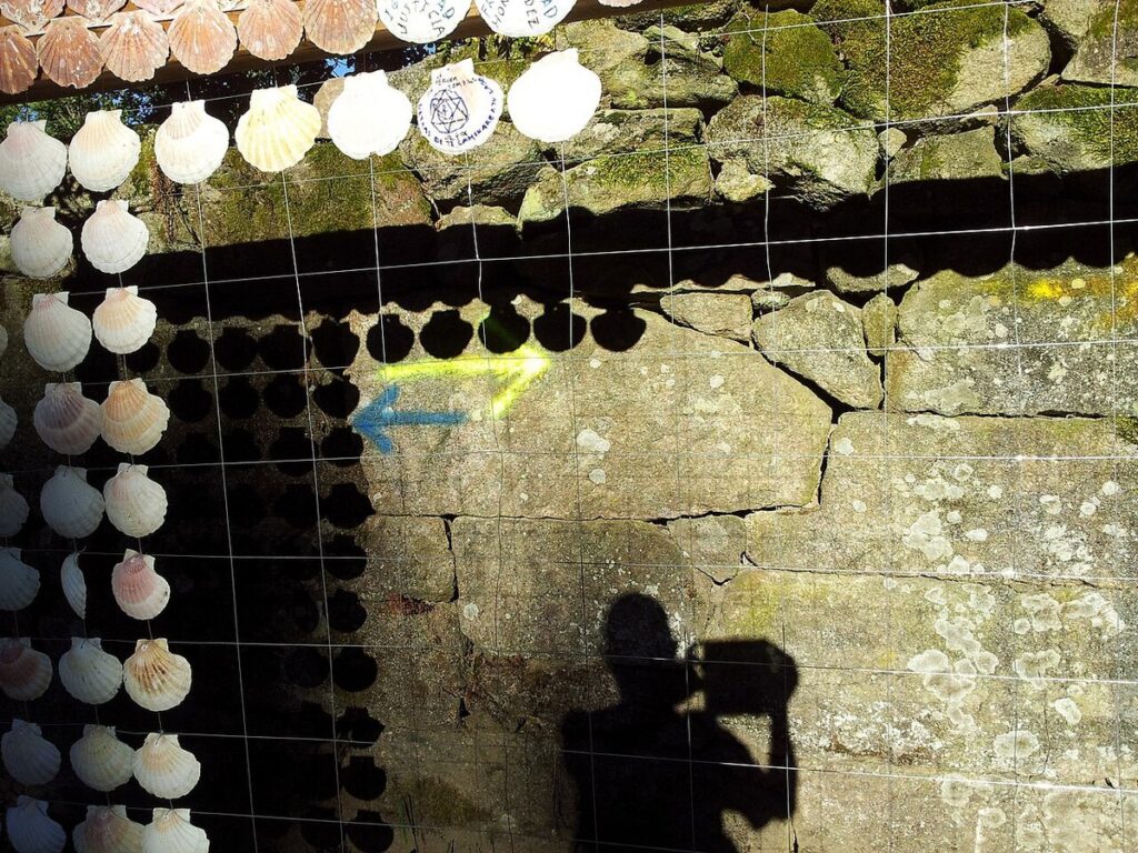 Frecce gialla e blu dipinte su un muro di pietra in Portogallo: verso Santiago e verso Fátima