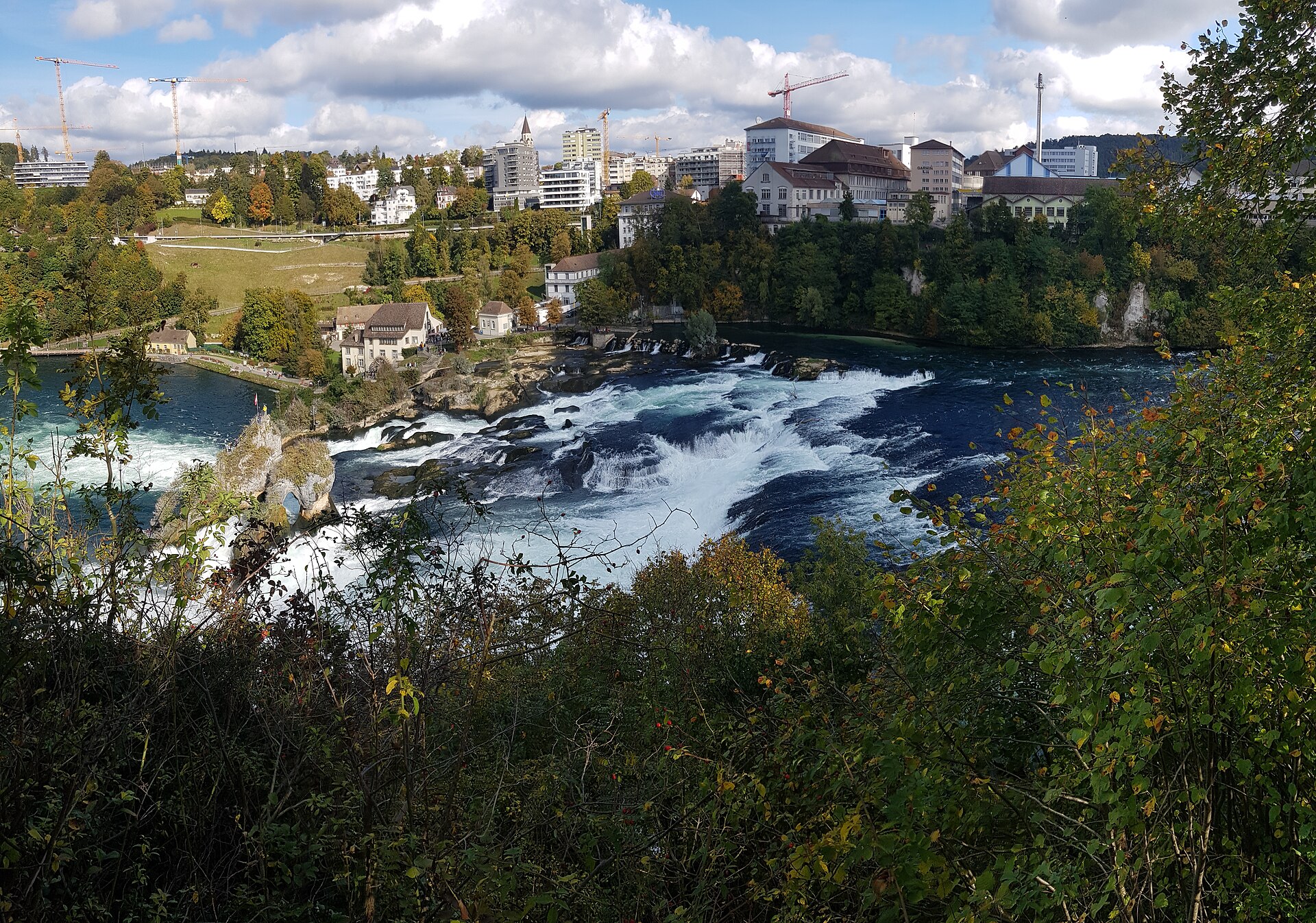 Le cascate del Reno in autunno con la vegetazione dai colori dorati e rossiccimi sulle sponde.