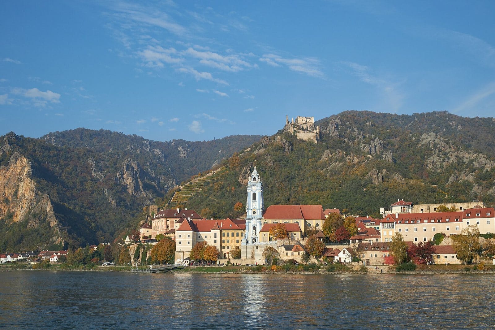 Dürnstein sul Danubio a metà ottobre, con il campanile azzurro dell'abbazia, le rovine del castello e i boschi autunnali