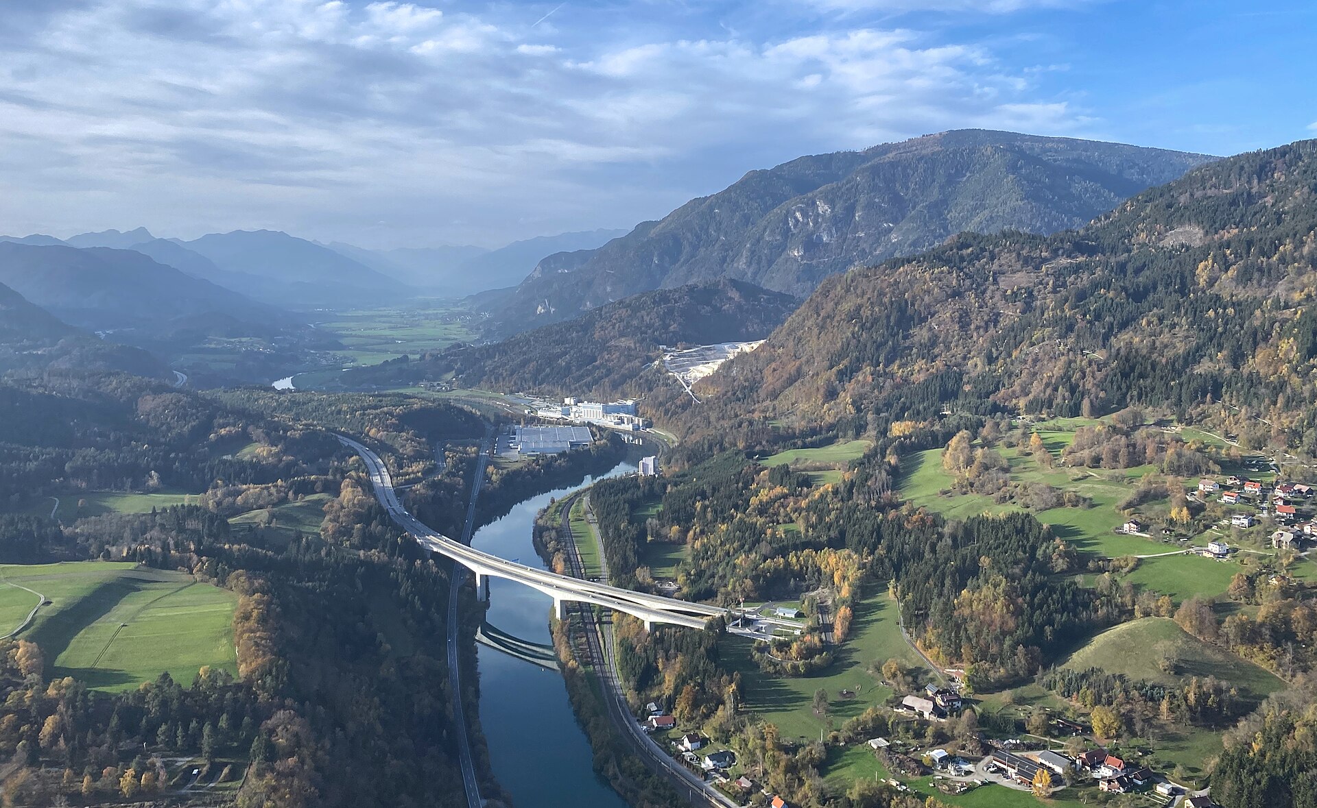 Il fiume Drava scorre attraverso la valle austriaca con i boschi autunnali sulle pendici circostanti, una delle tappa principali del percorso ciclabile.