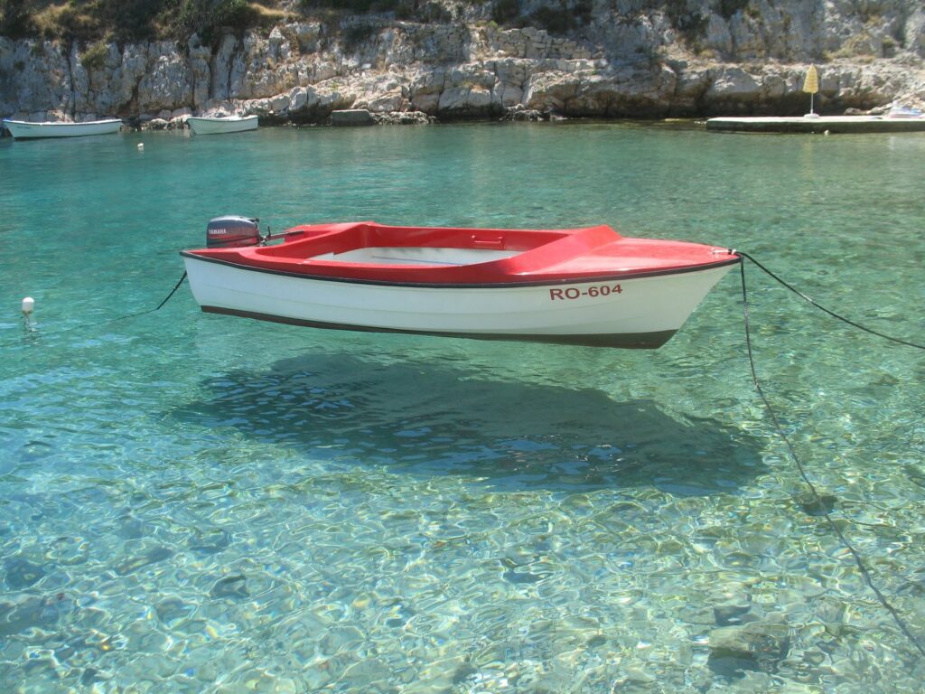 Una barca sull'acqua trasparentissima di una baia dell'isola di Šolta