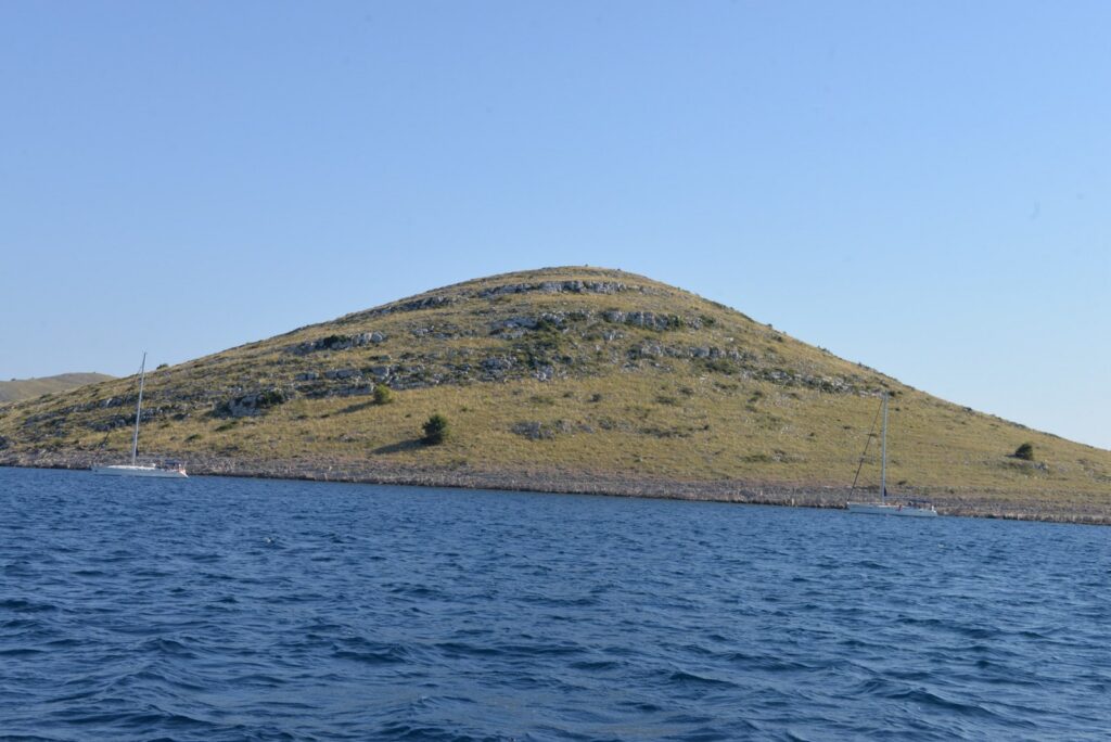 Un'isola brulla e rocciosa dell'Adriatico croato con due barche a vela ancorate