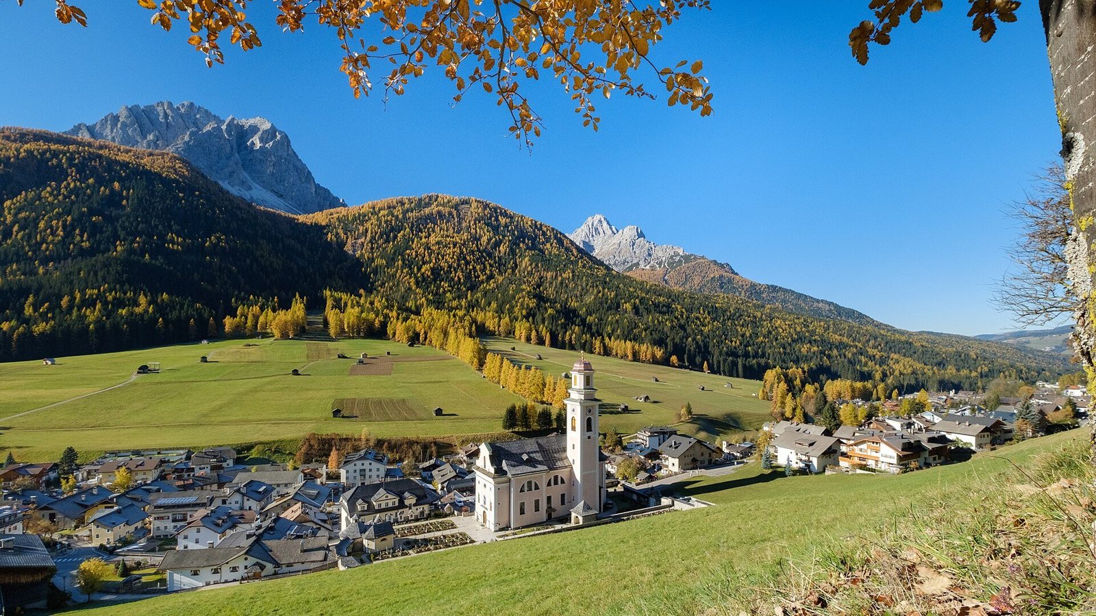 Sesto in Alta Val Pusteria a fine ottobre, con i larici dorati sulle pendici e le Dolomiti di Sesto sullo sfondo