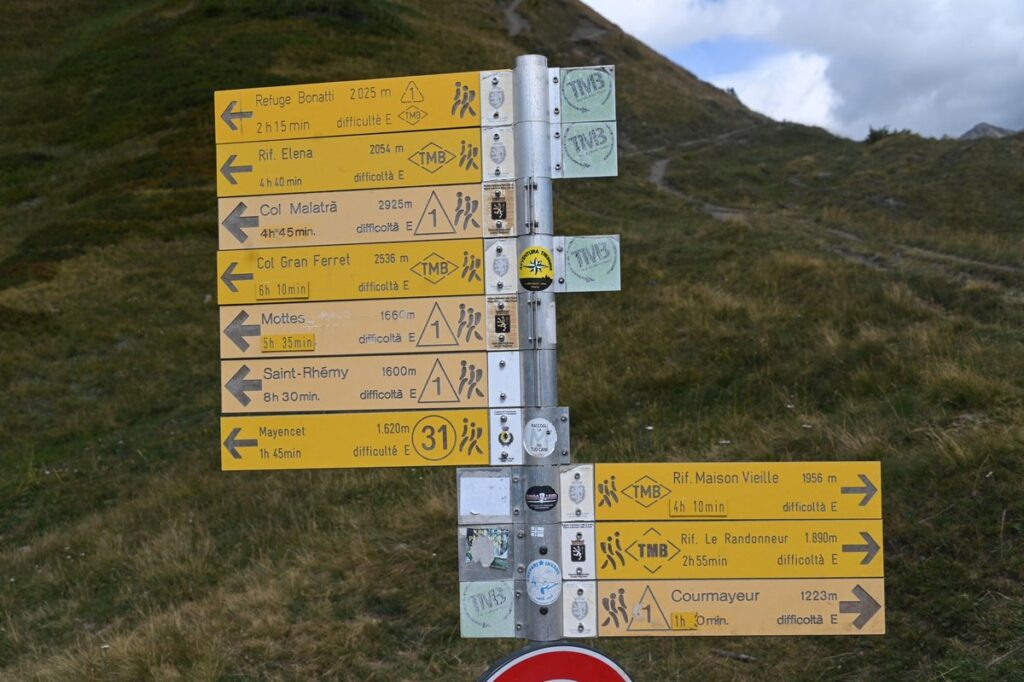 Palina gialla con i cartelli del Tour del Monte Bianco verso il rifugio Bonatti e il Col del Gran Ferret, in Val Ferret